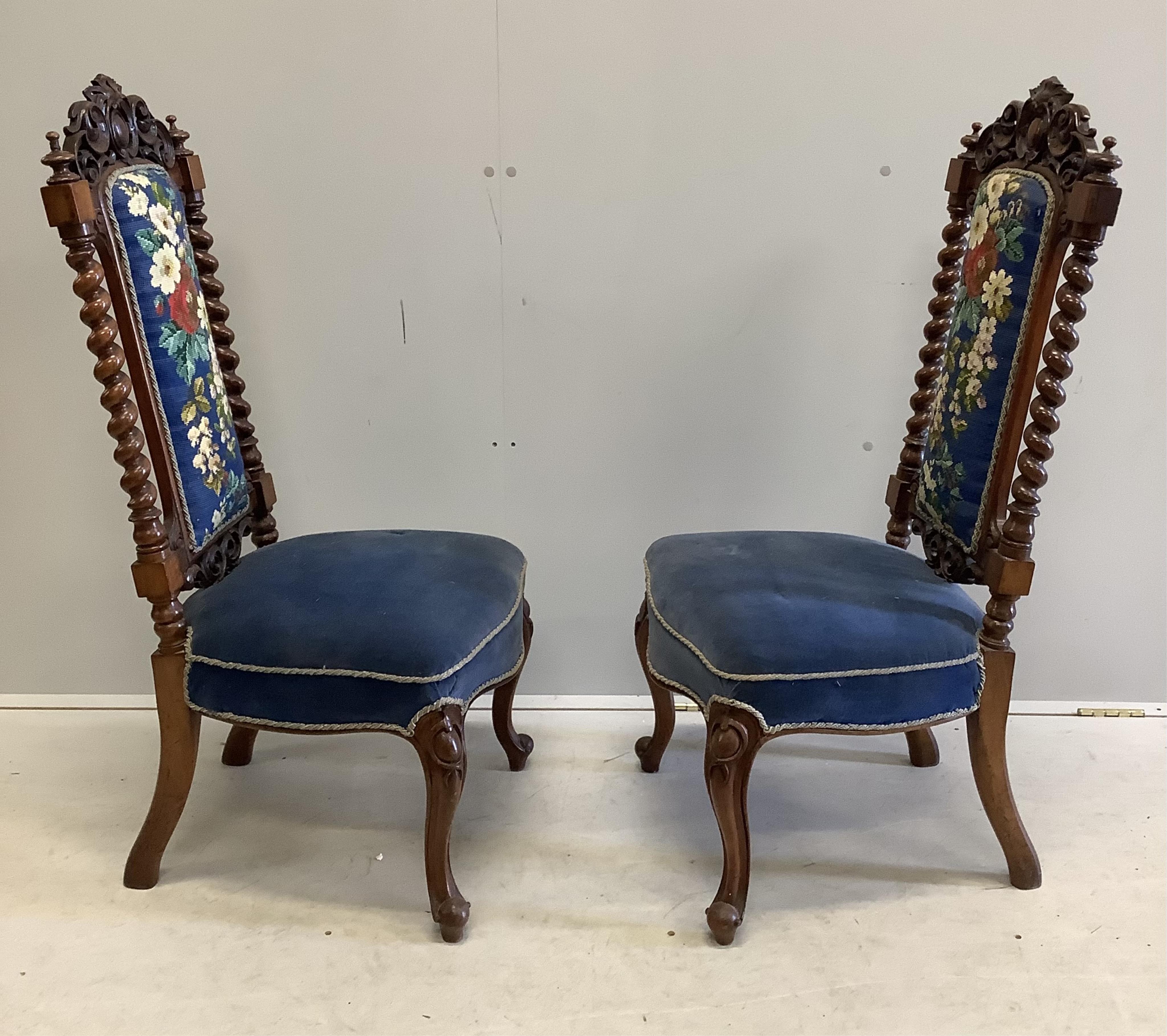 A pair of Victorian carved walnut side chairs with polychrome floral upholstered backs, width 46cm, depth 40cm, height 104cm. Condition - fair to good